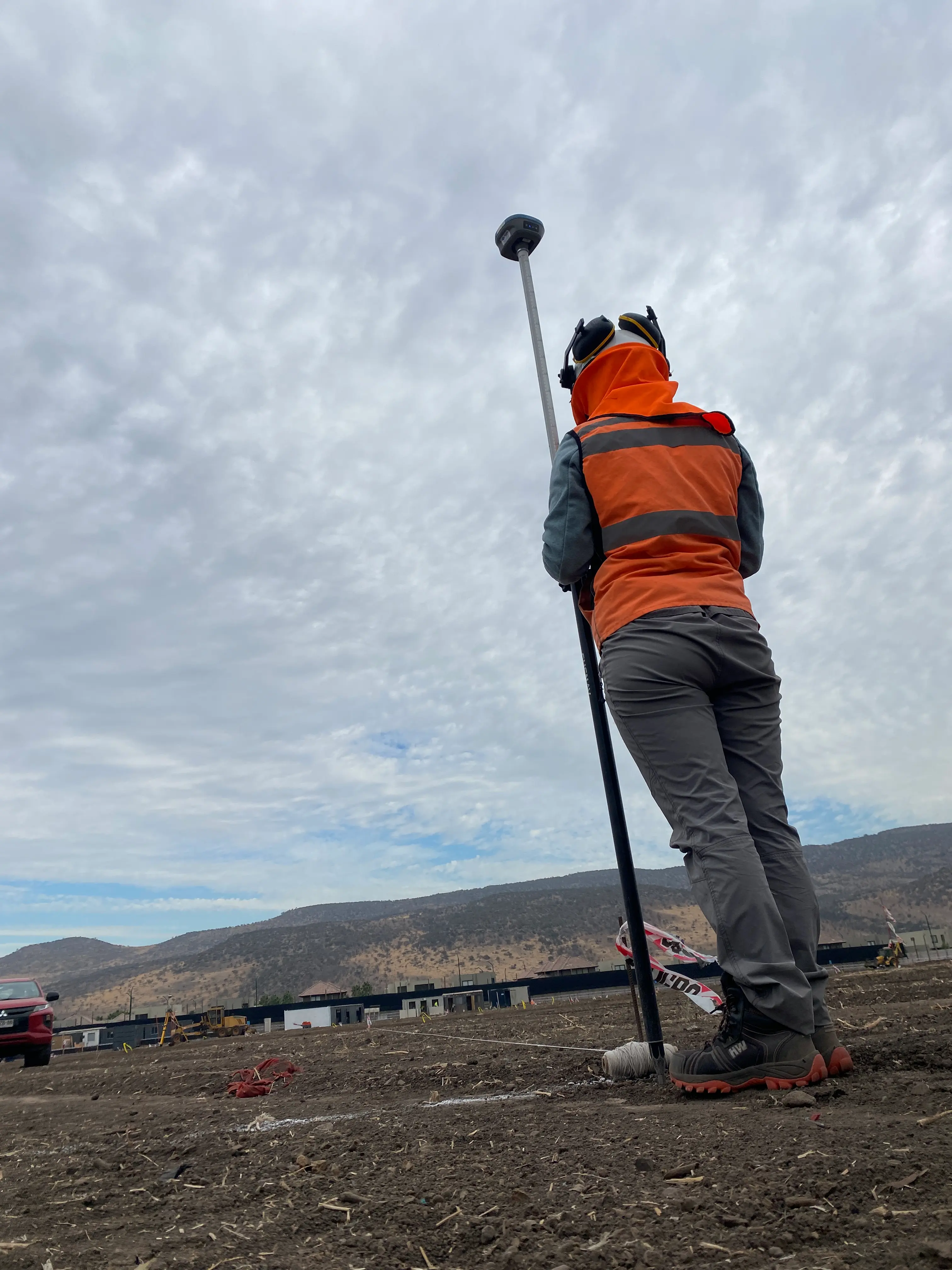 Topógrafa con GNSS, cielo dramático